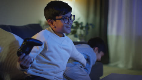 Two-Young-Boys-At-Home-Having-Fun-Playing-With-Computer-Games-Console-On-TV-Fighting-Over-Controllers-Late-At-Night-1